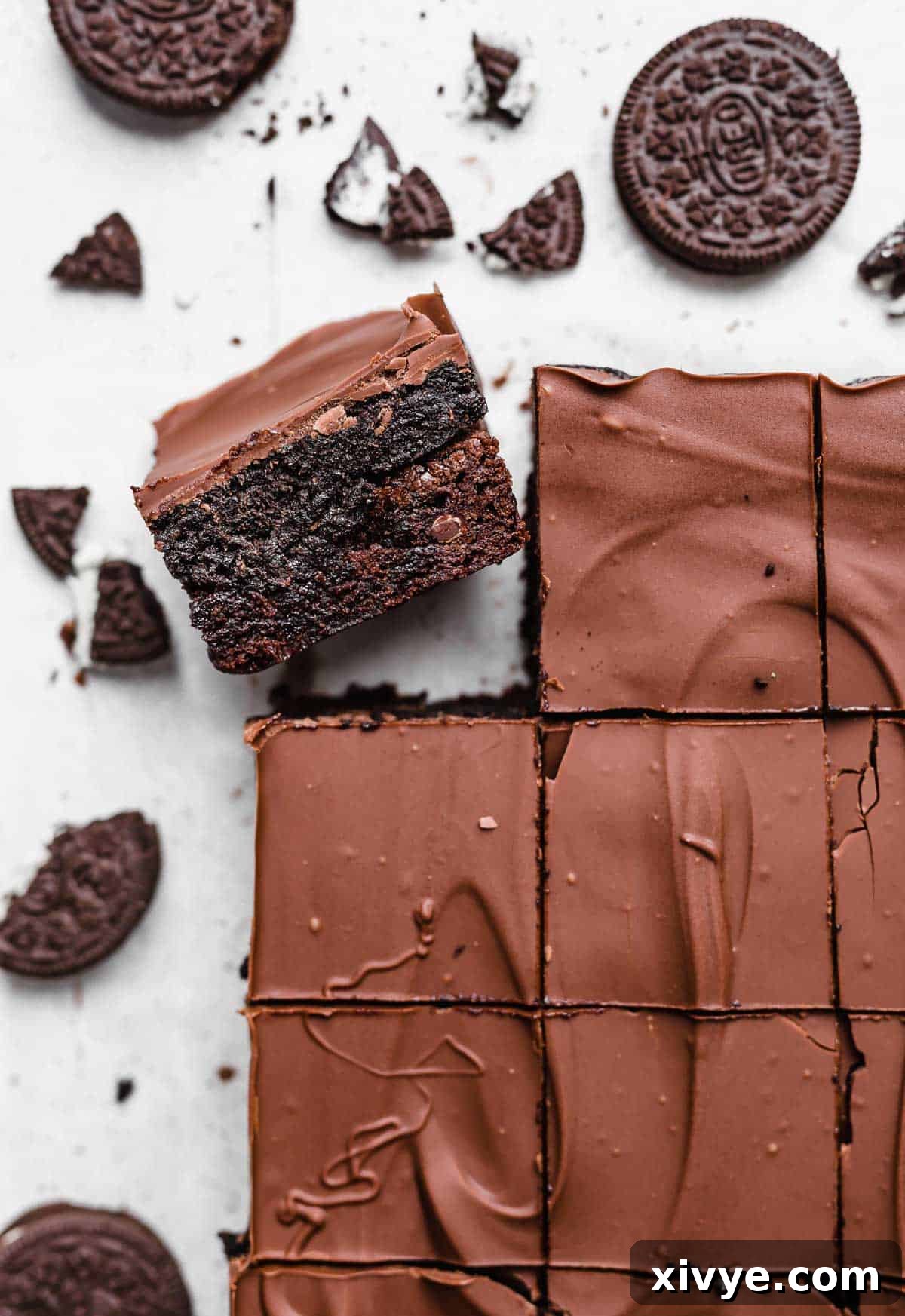 Decadent Oreo Truffle Brownies 2 An Oreo Truffle Brownie on a white background with oreo crumbs scattered around it.