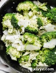 A pepper-sprinkled Broccoli Caesar Salad in a black bowl, illustrating a vibrant and healthy meal, garnished with fresh herbs.