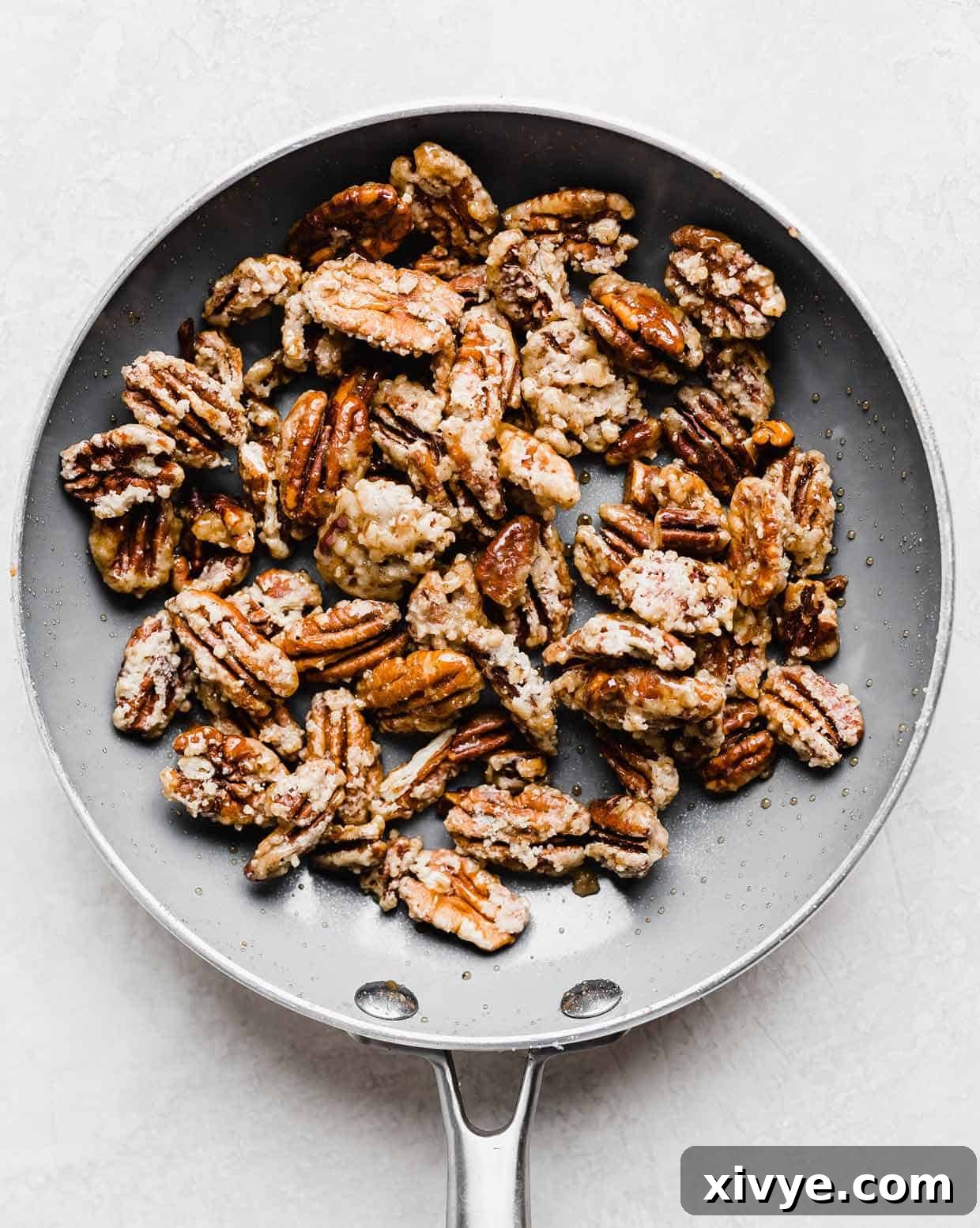 Perfectly sugared pecans showcased in a gray skillet, now beautifully coated in melted, caramelized sugar and lightly browned, ready to cool.