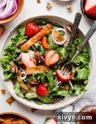 A fresh Strawberry Spinach Salad recipe topped with a homemade strawberry dressing, red onion, candied pecans, fried wontons.