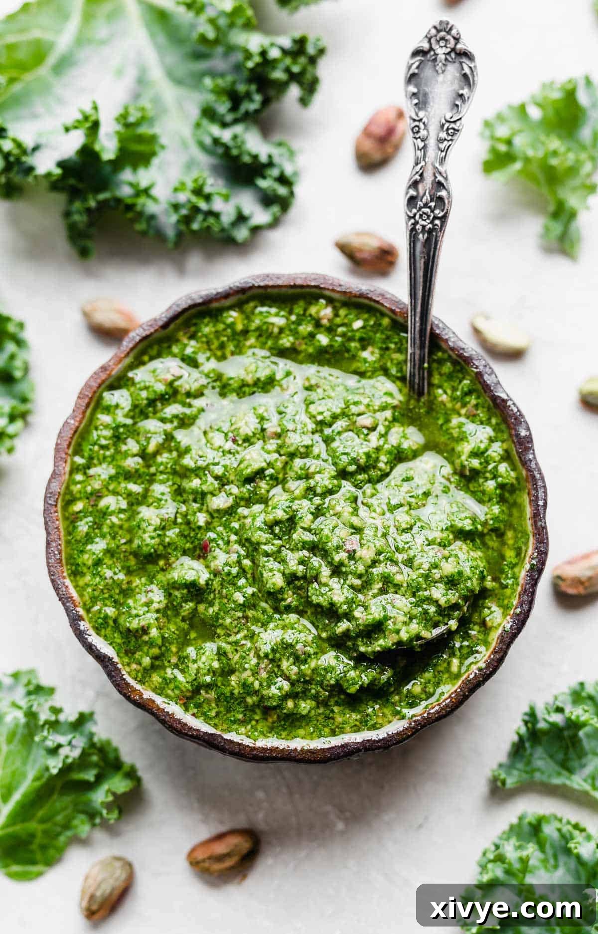 Healthy Homemade Kale Pesto 2 Overhead photo of Kale Pesto in a black bowl surrounded by pistachios.