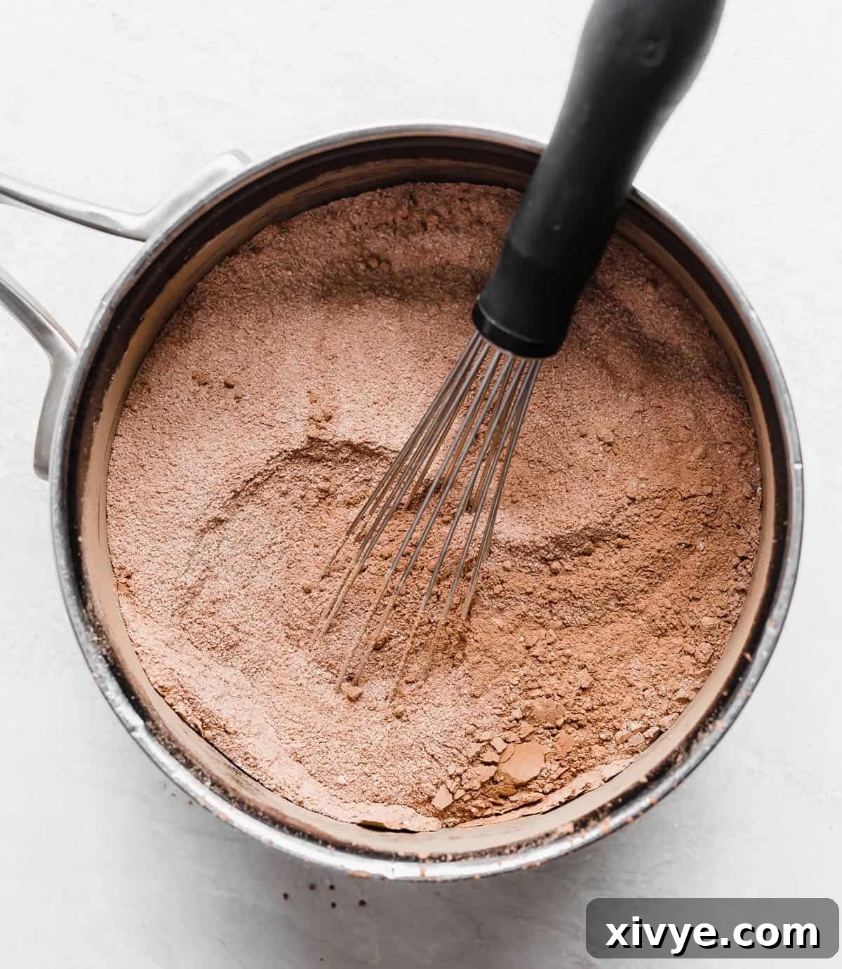 Classic Hot Fudge Sauce 5 A whisk mixing a light brown dry mixture in a saucepan, in preparation to making hot fudge sauce.