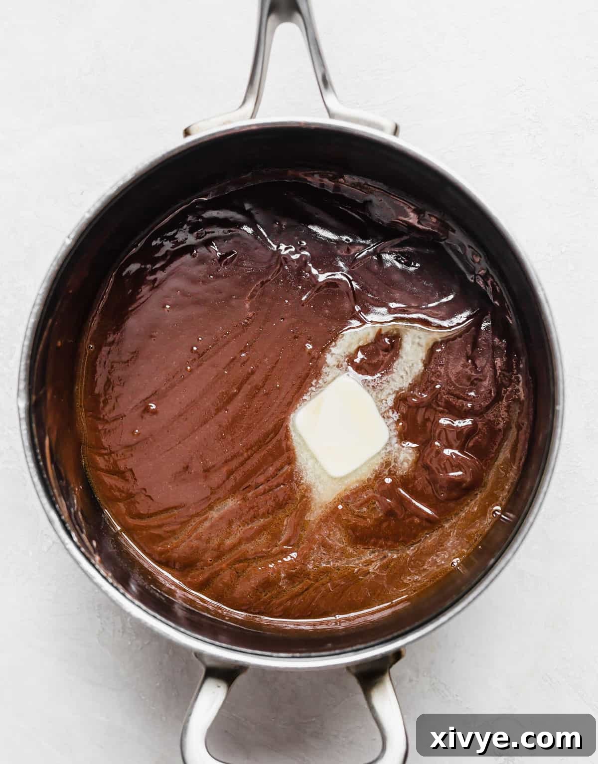 Classic Hot Fudge Sauce 8 A tablespoon of butter melting into homemade hot fudge sauce in a saucepan.