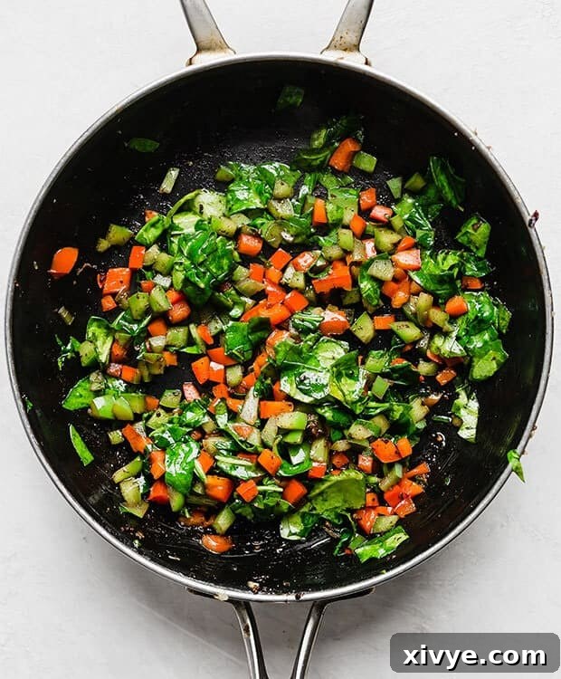 Simple Breakfast Bake 6 Diced red and green bell peppers mixed with fresh, chopped spinach wilting in a hot skillet, ready to be added to the breakfast casserole.