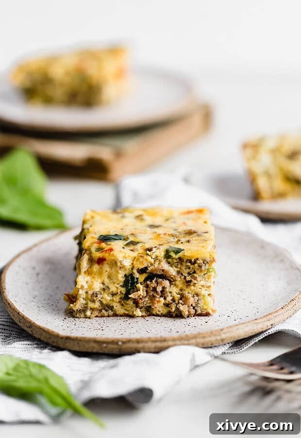 Simple Breakfast Bake 9 A perfectly portioned slice of golden-brown Breakfast Casserole, showcasing the layers of eggs, sausage, spinach, and cheese, served on a white plate with a fork.