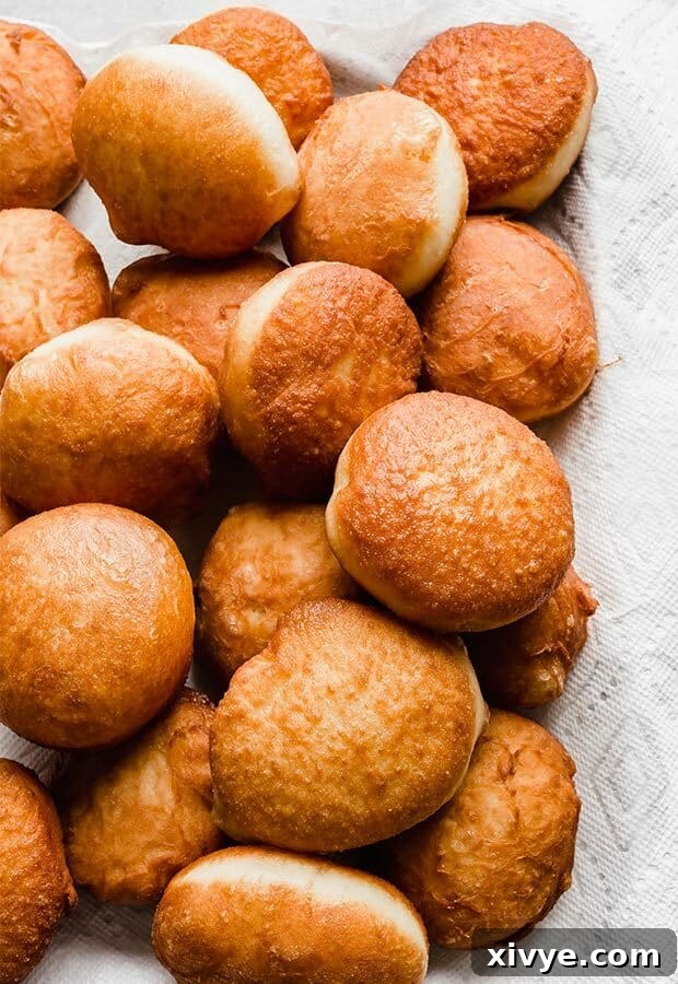 Freshly fried doughnuts on a tray.
