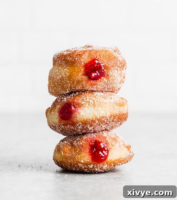 A stack of 3 donuts filled with raspberry jam.