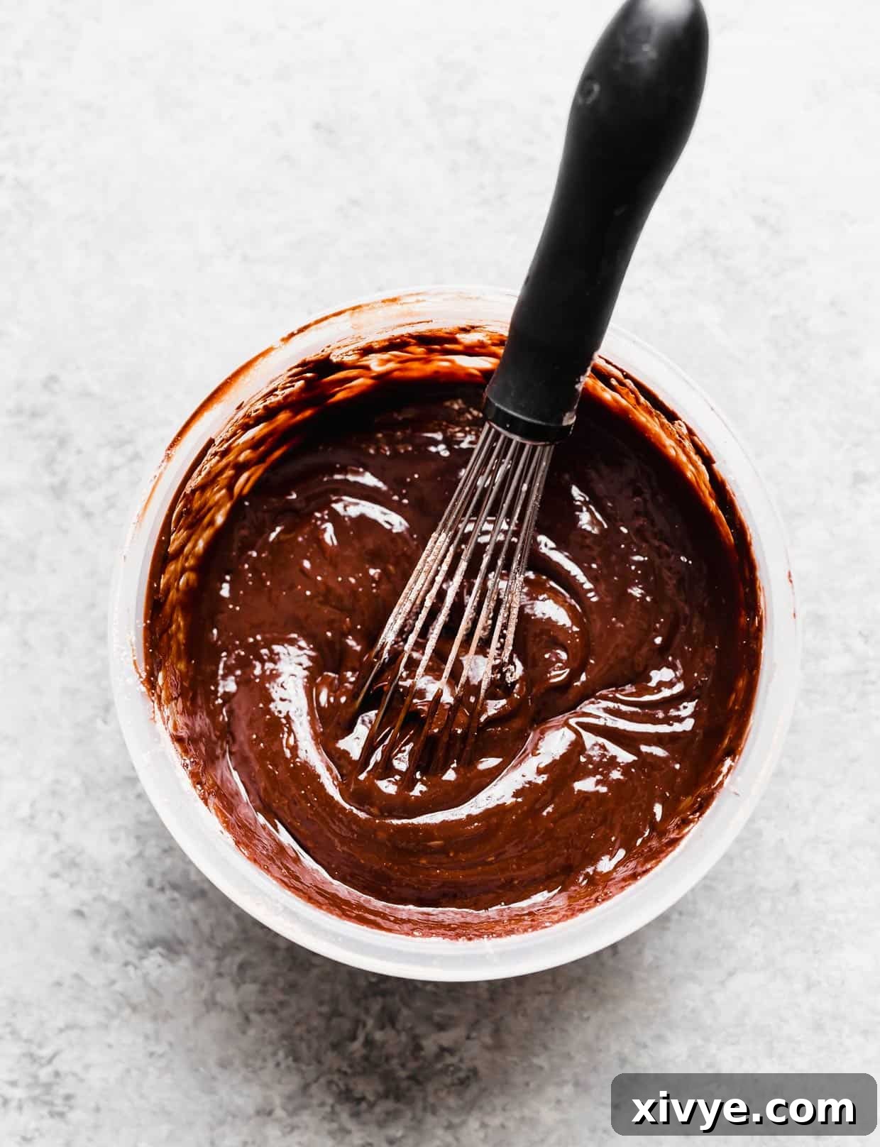 Perfect Homemade Boston Cream Donuts 5 A melty chocolate glaze in a bowl with a whisk in it.