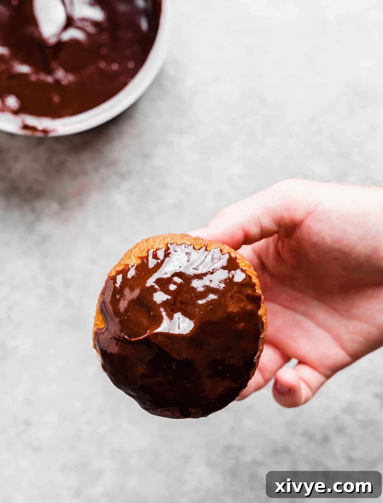 Perfect Homemade Boston Cream Donuts 7 A hand holding a chocolate dipped Boston Cream Donut.