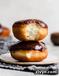 Perfect Homemade Boston Cream Donuts 8 Two Boston Cream Donuts on a white plate against a light grey background.