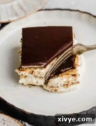 A fork cutting into a square of chocolate topped Chocolate Eclair Cake.