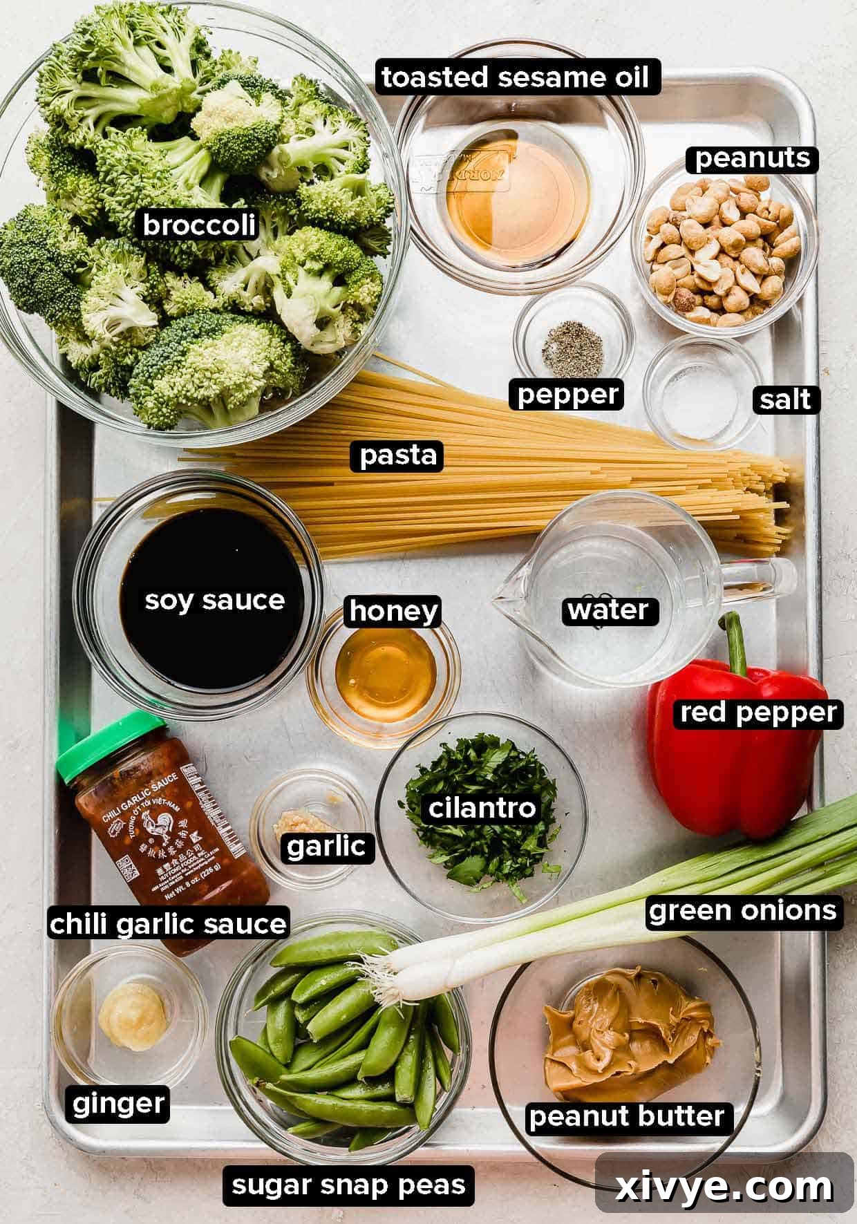 Peanut Noodles with Vegetables ingredients on a baking sheet, vegetables include broccoli, red pepper, green onion, sugar snap peas, cilantro.