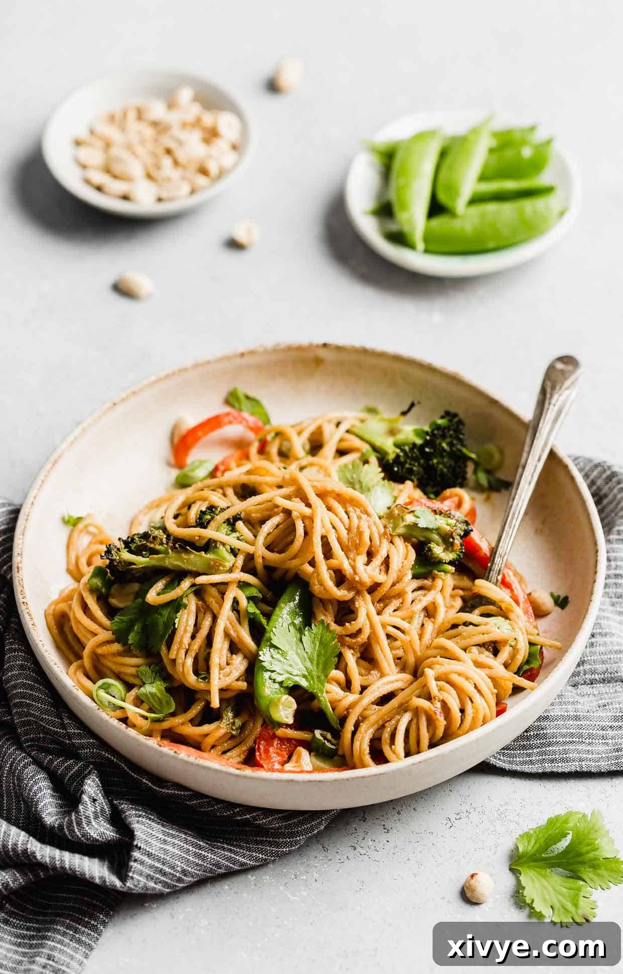 A white plate with Peanut Noodles with Vegetables on it, on a white background. 