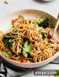 Peanut butter noodles with vegetables on a pasta plate.
