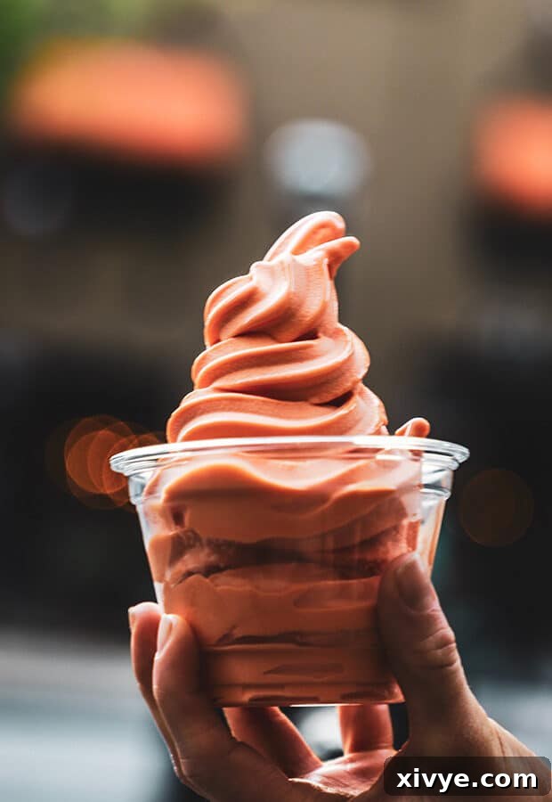 Midweek Sweetness 2 A hand holding a cup of vibrant pink and orange ice cream, suggesting a refreshing summer treat perfect for warm weather enjoyment.