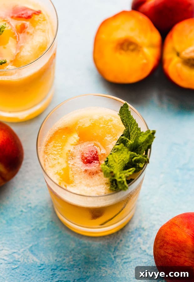 A vibrant glass of orange peach punch, garnished with fresh peach slices, ready to be enjoyed.