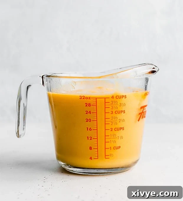 A 4 cup glass measuring cup full of vibrant, smooth pureed peaches.