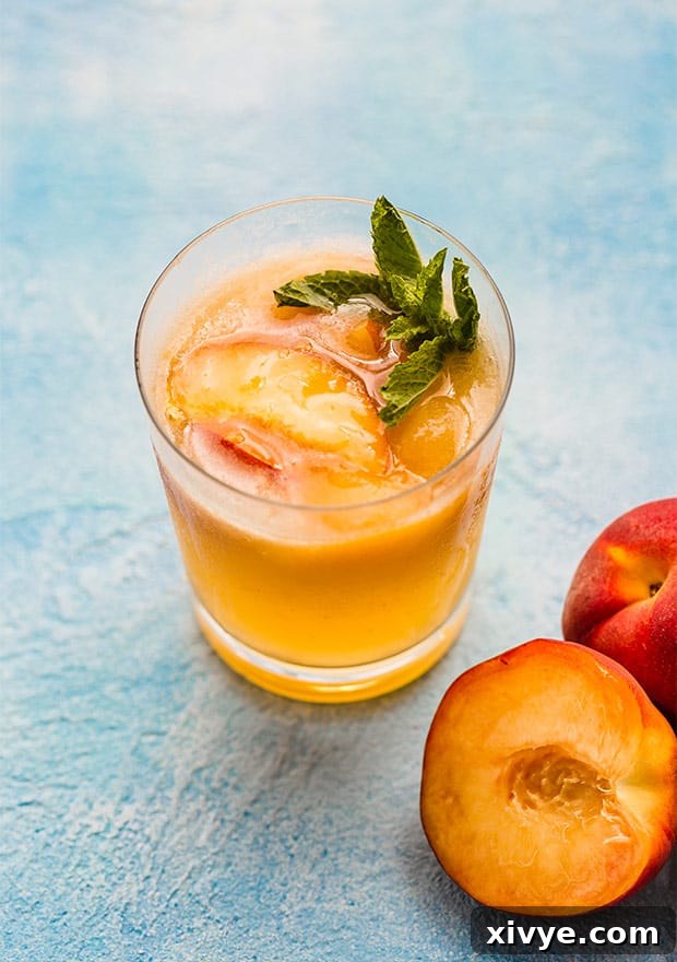 A glass of peach punch elegantly garnished with a sprig of fresh mint, adding a touch of sophistication.