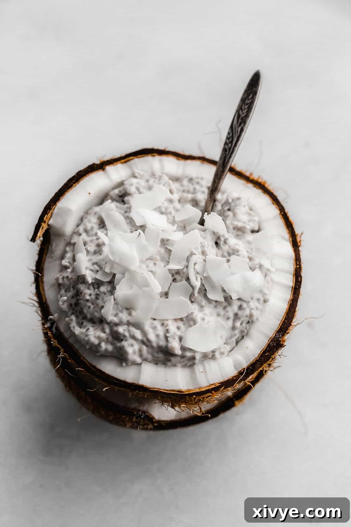 Overnight Coconut Chia Pudding topped with flaky coconut on a white background.