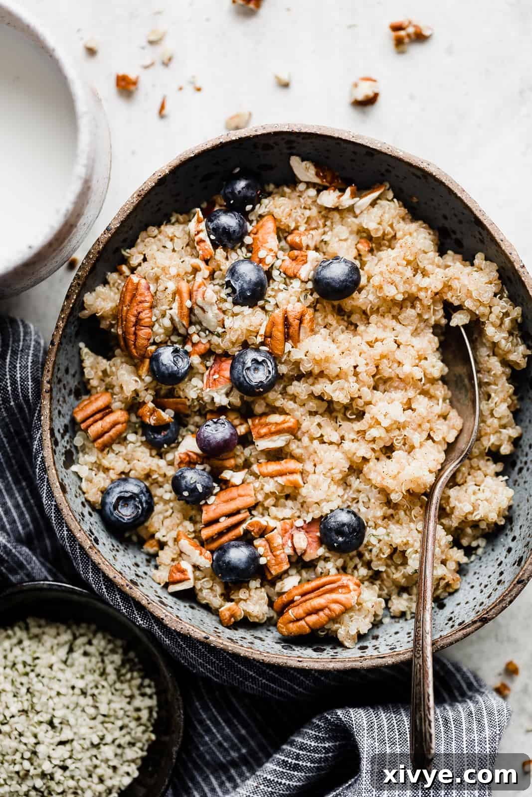 Wholesome Quinoa Porridge 2 A blue bowl full of breakfast quinoa topped with pecans and blueberries.