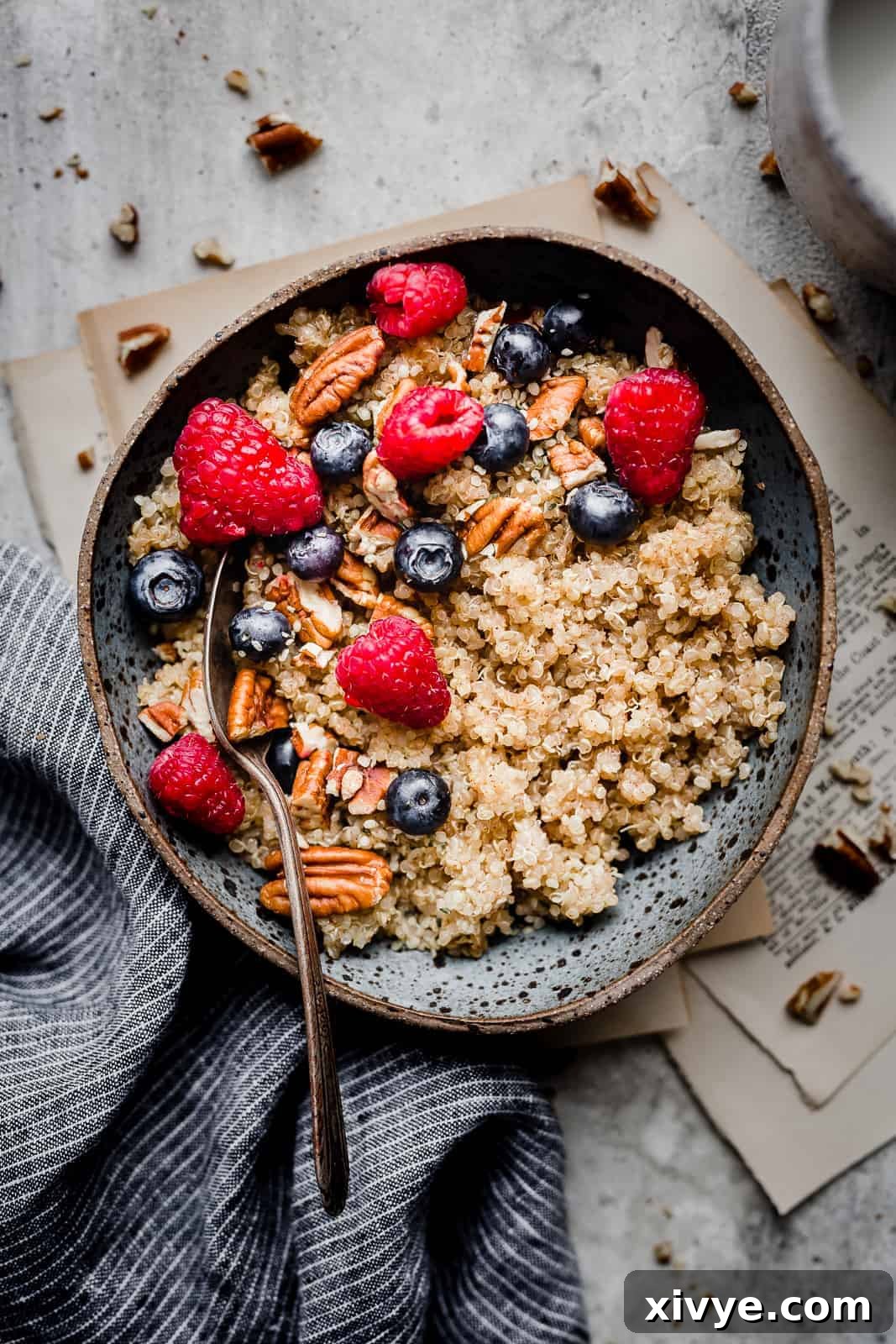 Wholesome Quinoa Porridge 8 A blue bowl with cooked quinoa that has been topped with fresh fruit.