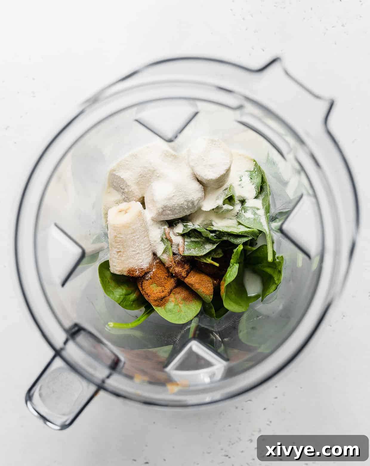 Energizing Banana Spinach Protein Smoothie 4 Overhead photo of a blender loaded with spinach, bananas, and ground cinnamon.