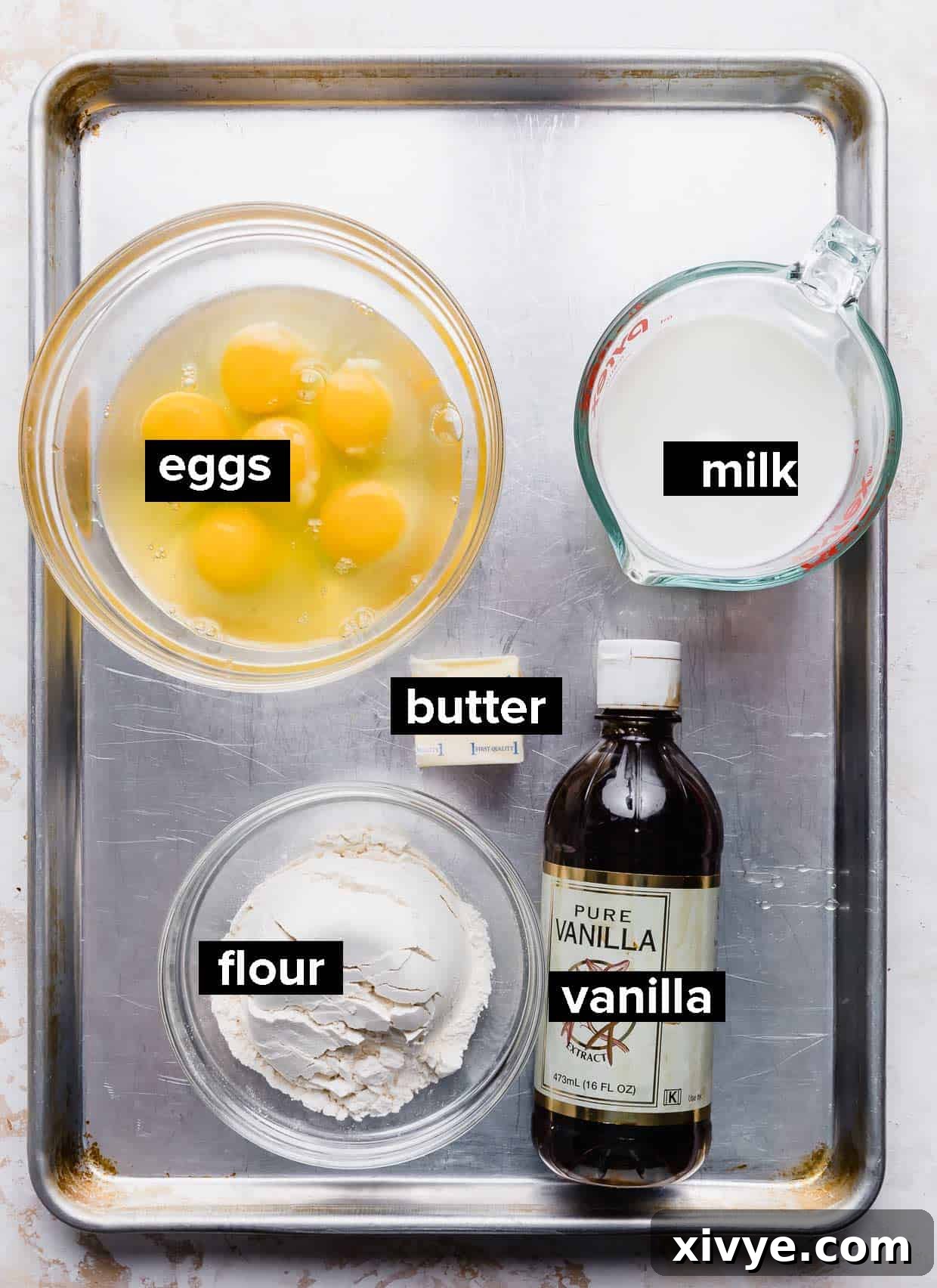 Ingredients used to make German pancakes on a baking sheet.