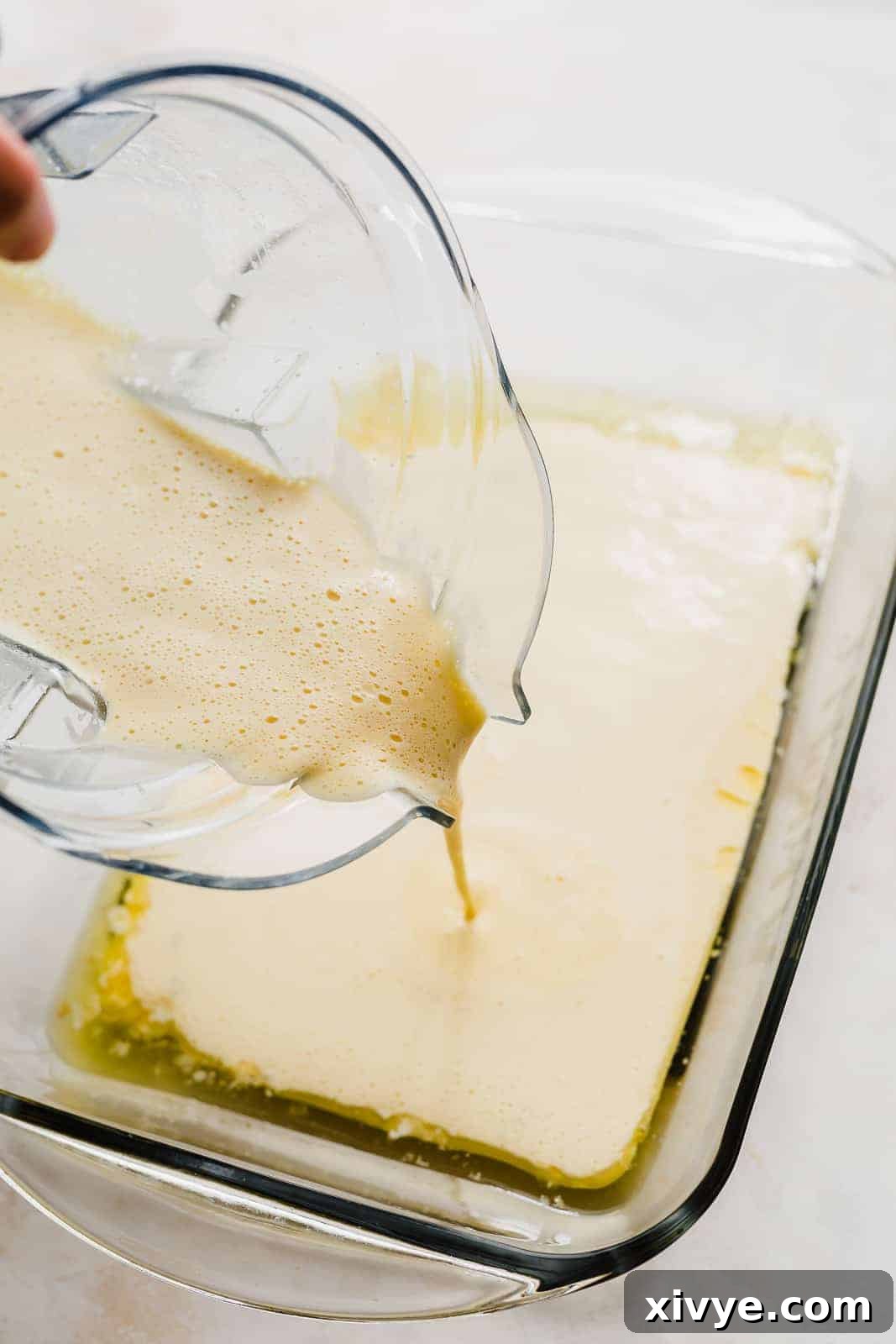 German Pancake batter being poured into a thirteen by nine inch casserole dish.
