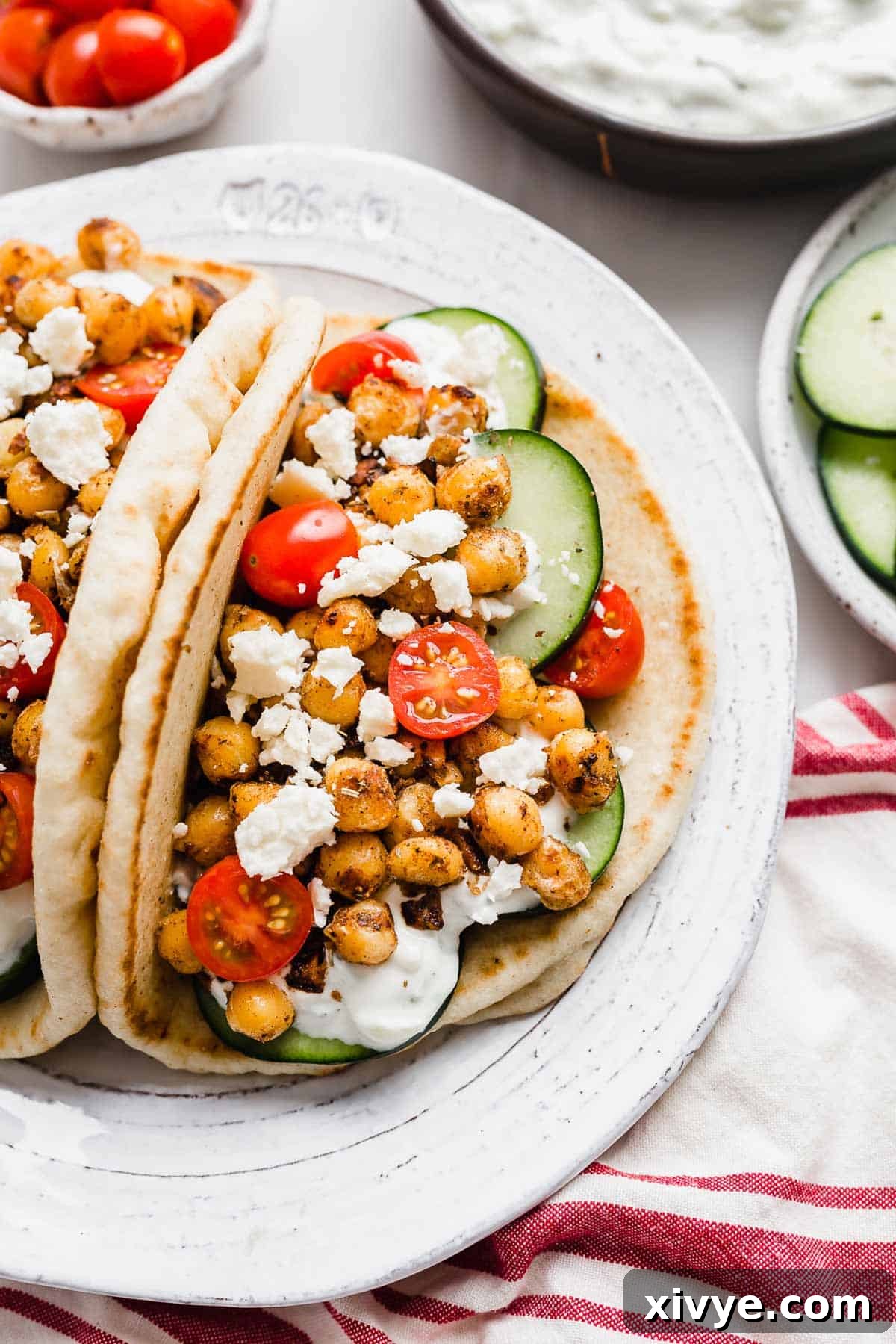 Mediterranean Chickpea Gyros 49 Chickpea Gyros on a white plate topped with cucumbers, cherry tomatoes, and feta cheese.