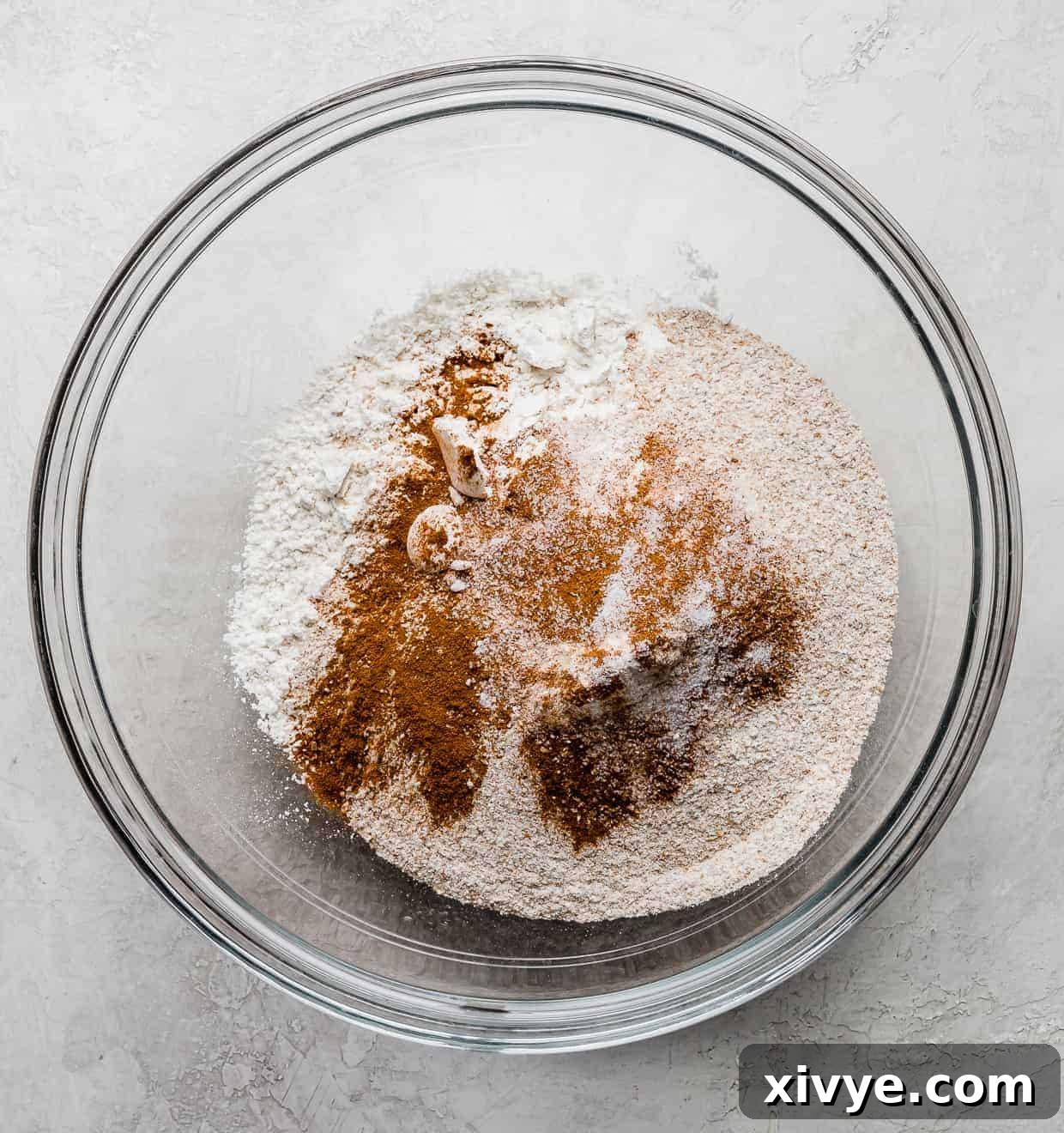 Dry ingredients (flour, whole wheat flour, sugar, cinnamon) in a glass bowl.