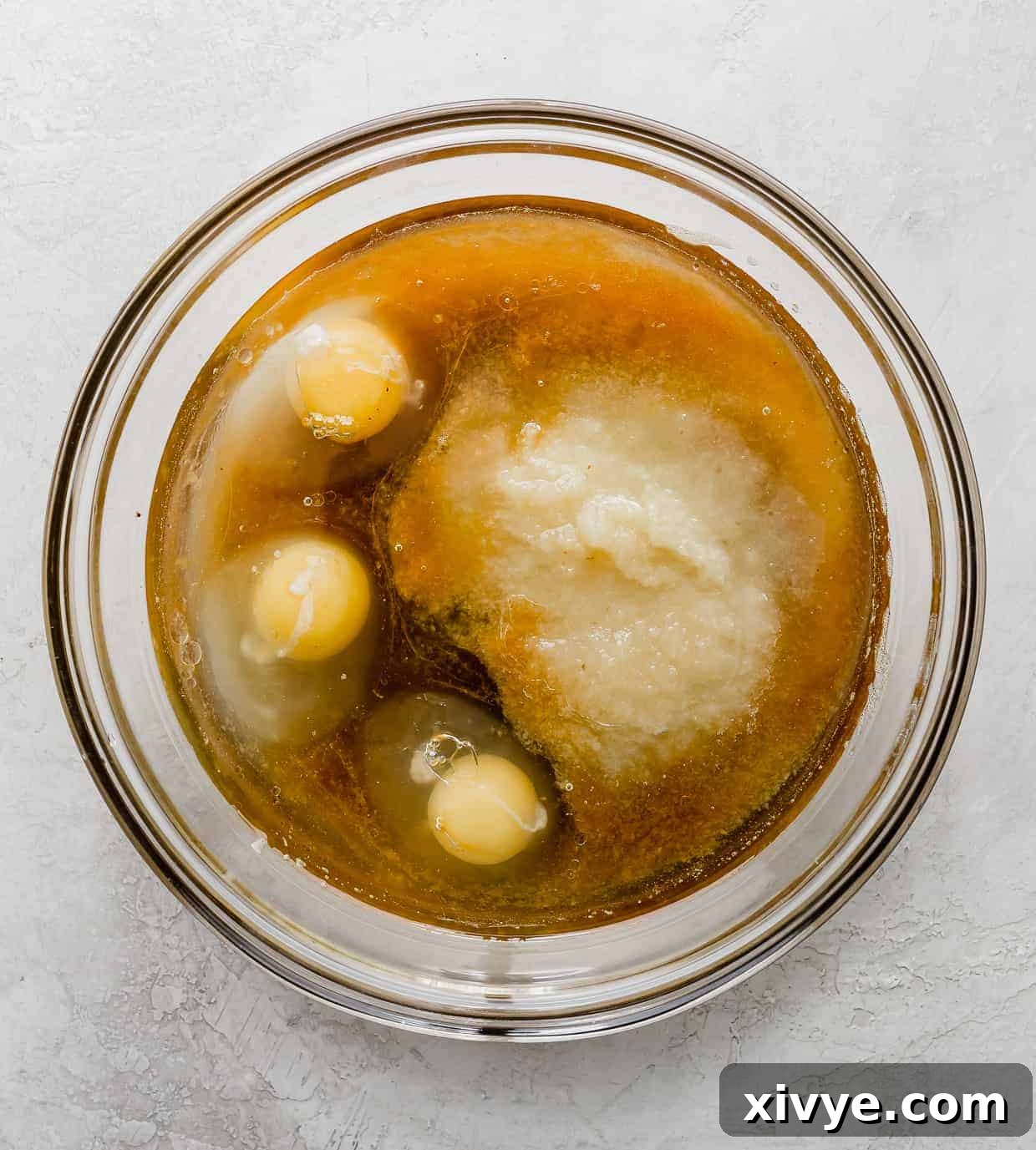 "Wet ingredients" in a glass bowl, consisting of 3 eggs, oil, apple sauce and vanilla.
