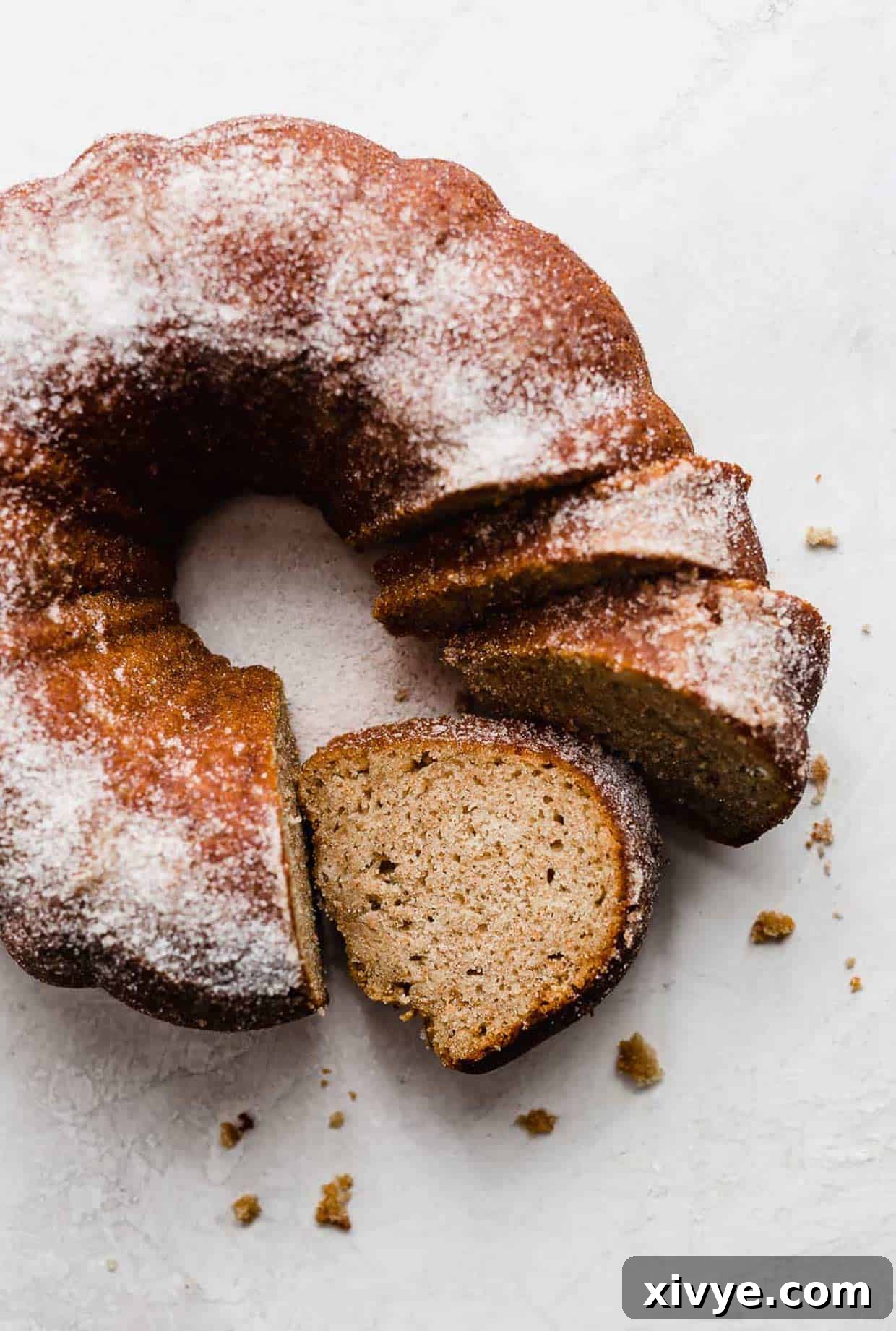 an apple cider coffee cake made in a bundt pan on a white background with three slices cut from the bundt cake.