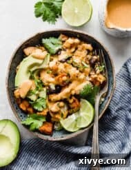 A blue bowl full of quinoa topped with roasted sweet potatoes and cauliflower.