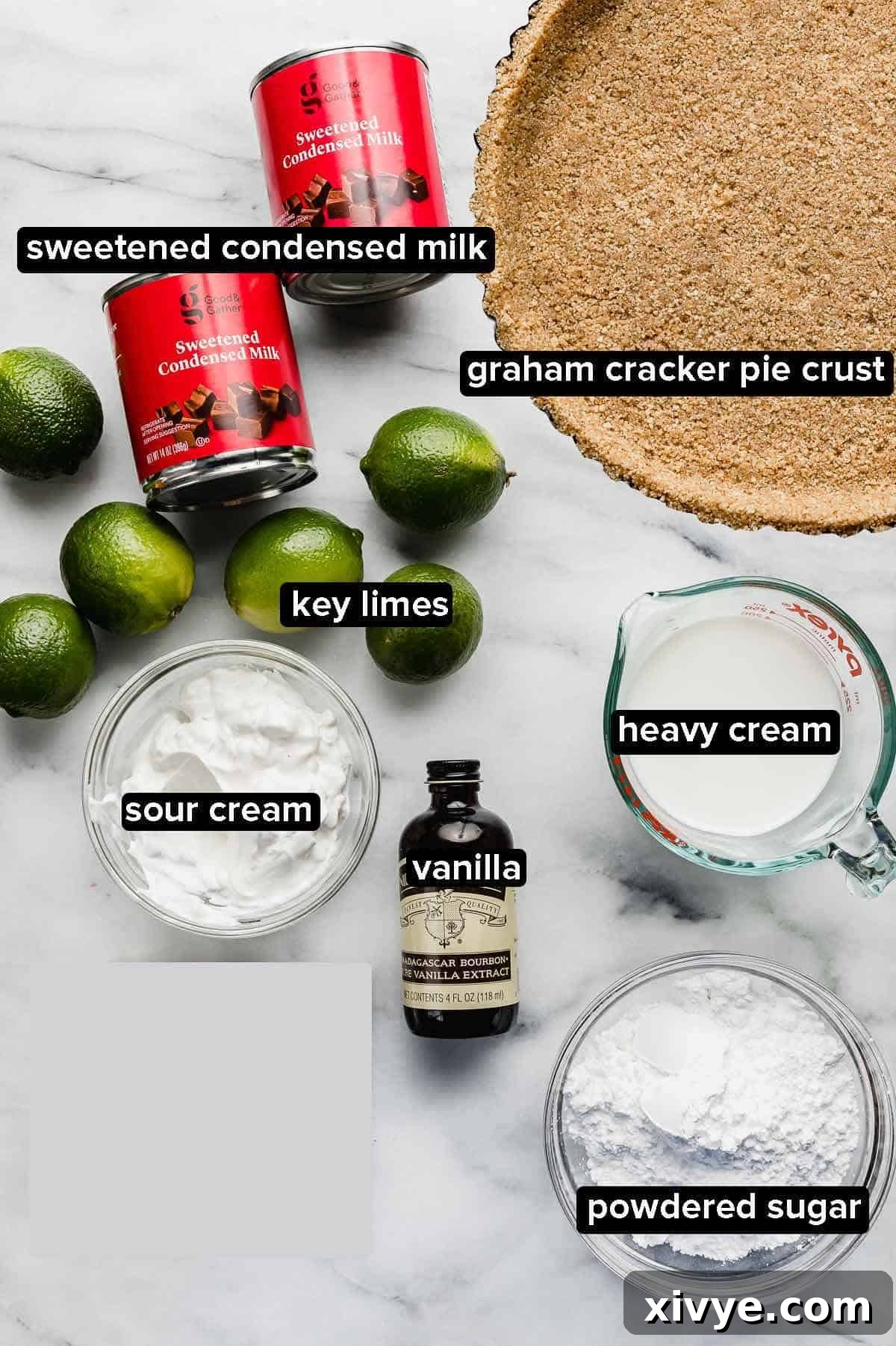 Velvet Key Lime Pie with a Sour Cream Kiss 3 A top-down shot of various ingredients for key lime pie with sour cream including fresh key limes, a can of sweetened condensed milk, a bowl of sour cream, and a homemade graham cracker crust.