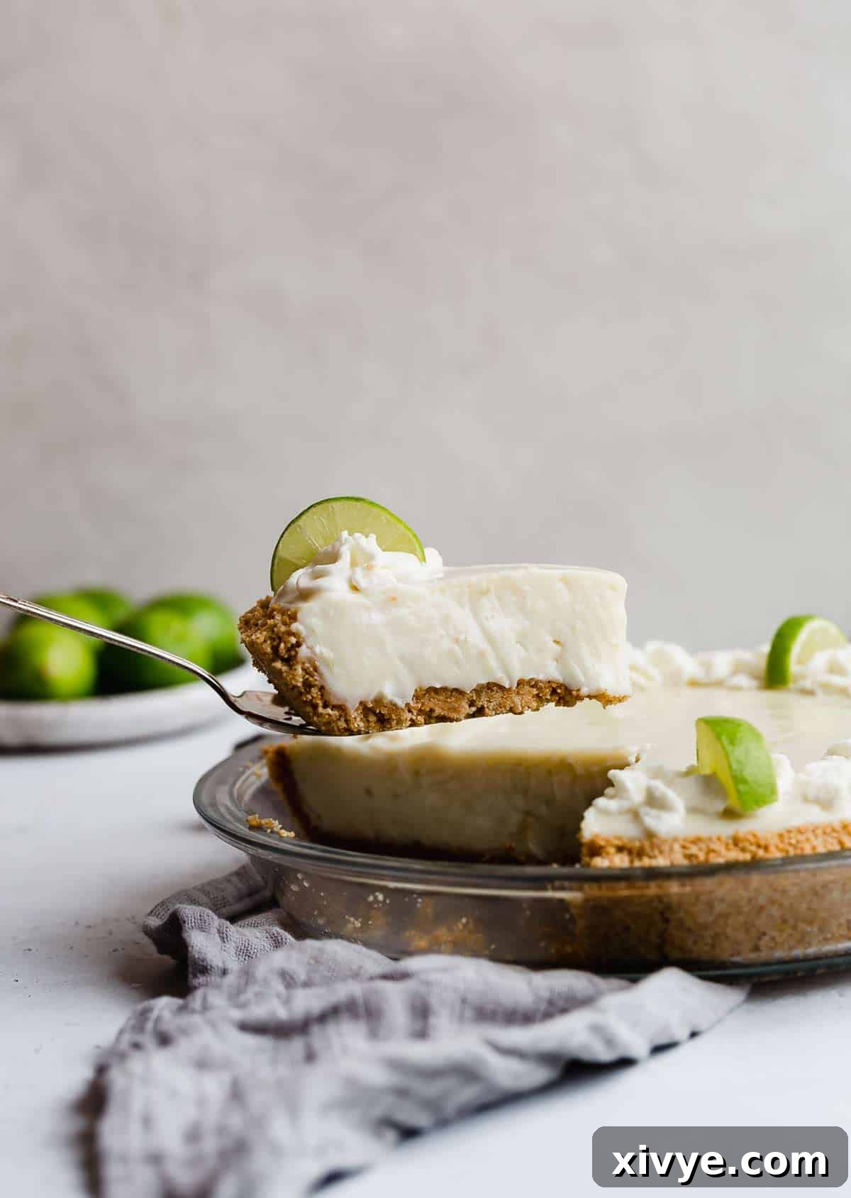 Velvet Key Lime Pie with a Sour Cream Kiss 6 A perfectly balanced slice of sour cream key lime pie on a pie server, showcasing its creamy filling and golden crust.