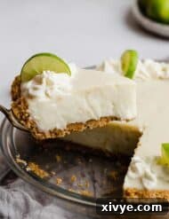 Velvet Key Lime Pie with a Sour Cream Kiss 8 A slice of Key Lime Pie with sour cream on a graham cracker crust balancing on a serving knife.