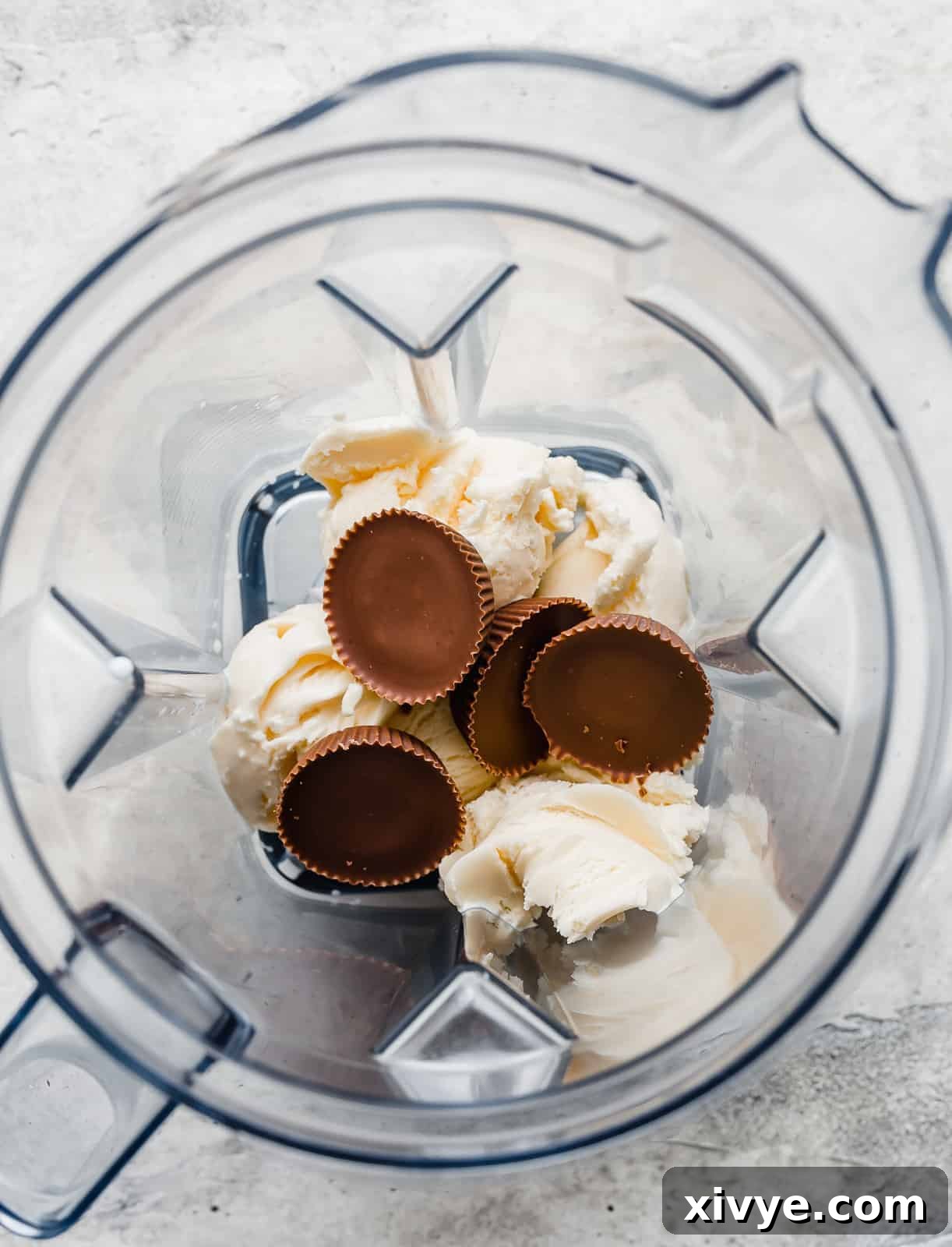 A blender with vanilla ice cream and 4 Reese's peanut butter cups in it.