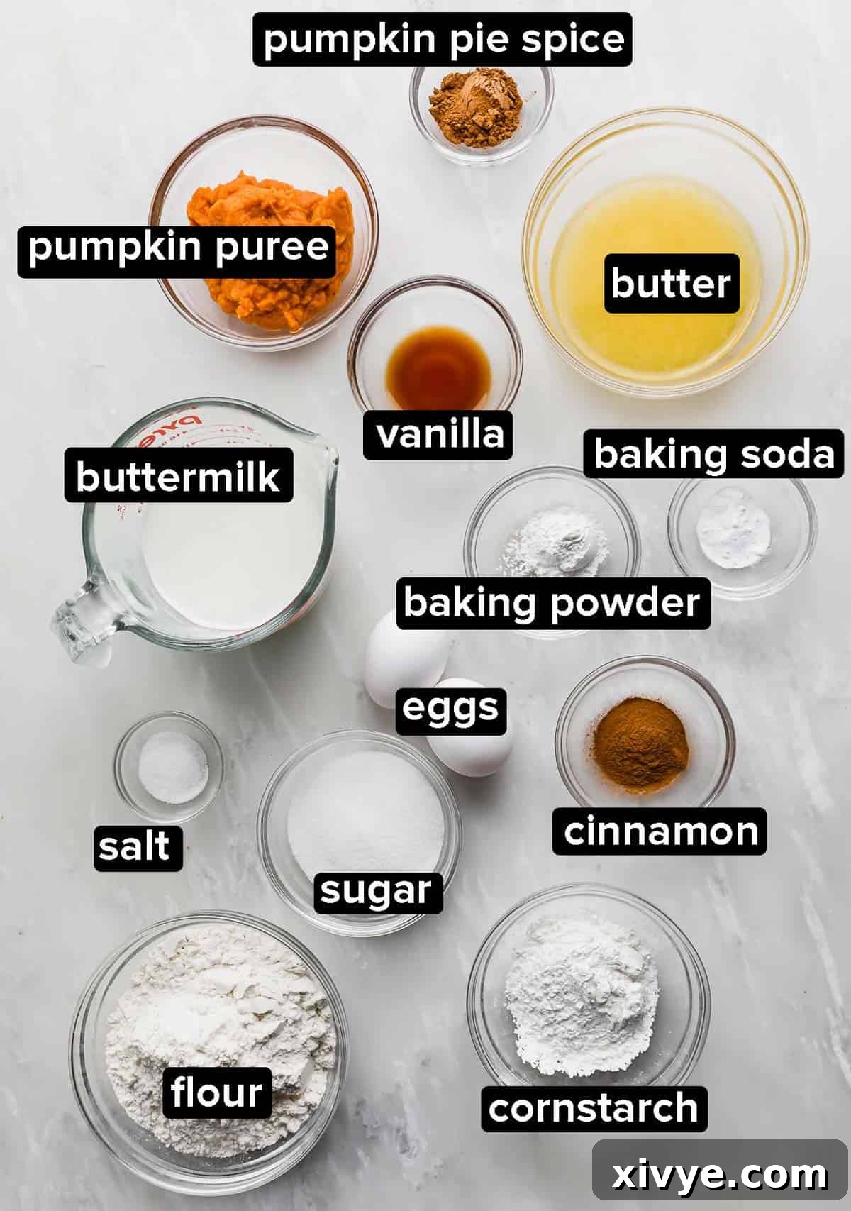 Various Buttermilk Pumpkin Waffle ingredients, including flour, sugar, butter, buttermilk, pumpkin puree, and spices, are artfully arranged on a elegant marble table.