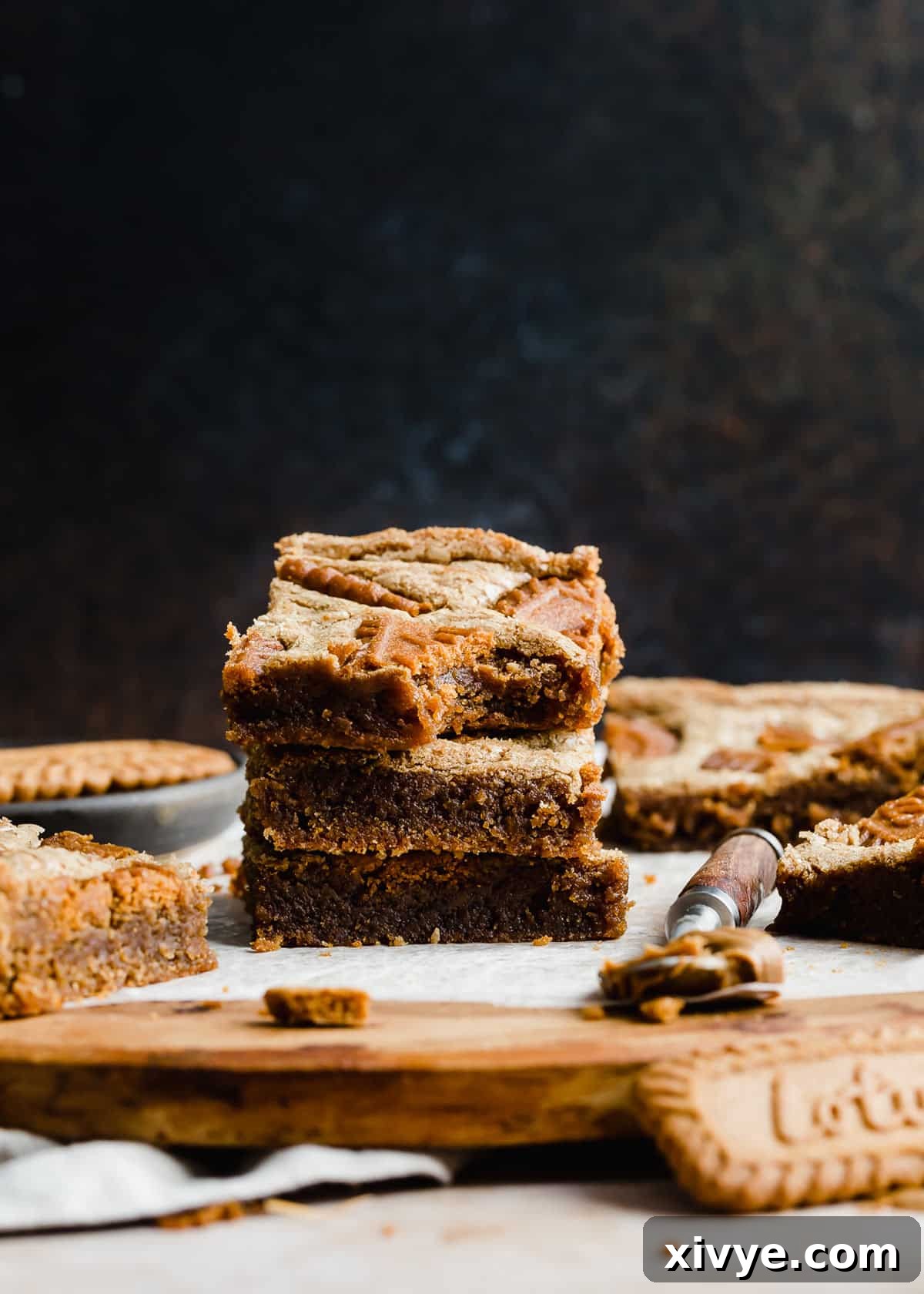 Three Biscoff Brownies stacked on top of each other in front of a black background.
