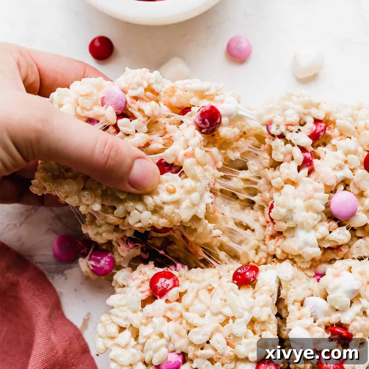 Colorful M&M Crispy Bars 8 A hand pulling a square of M&M Rice Krispie treats, showing its irresistible stretch.