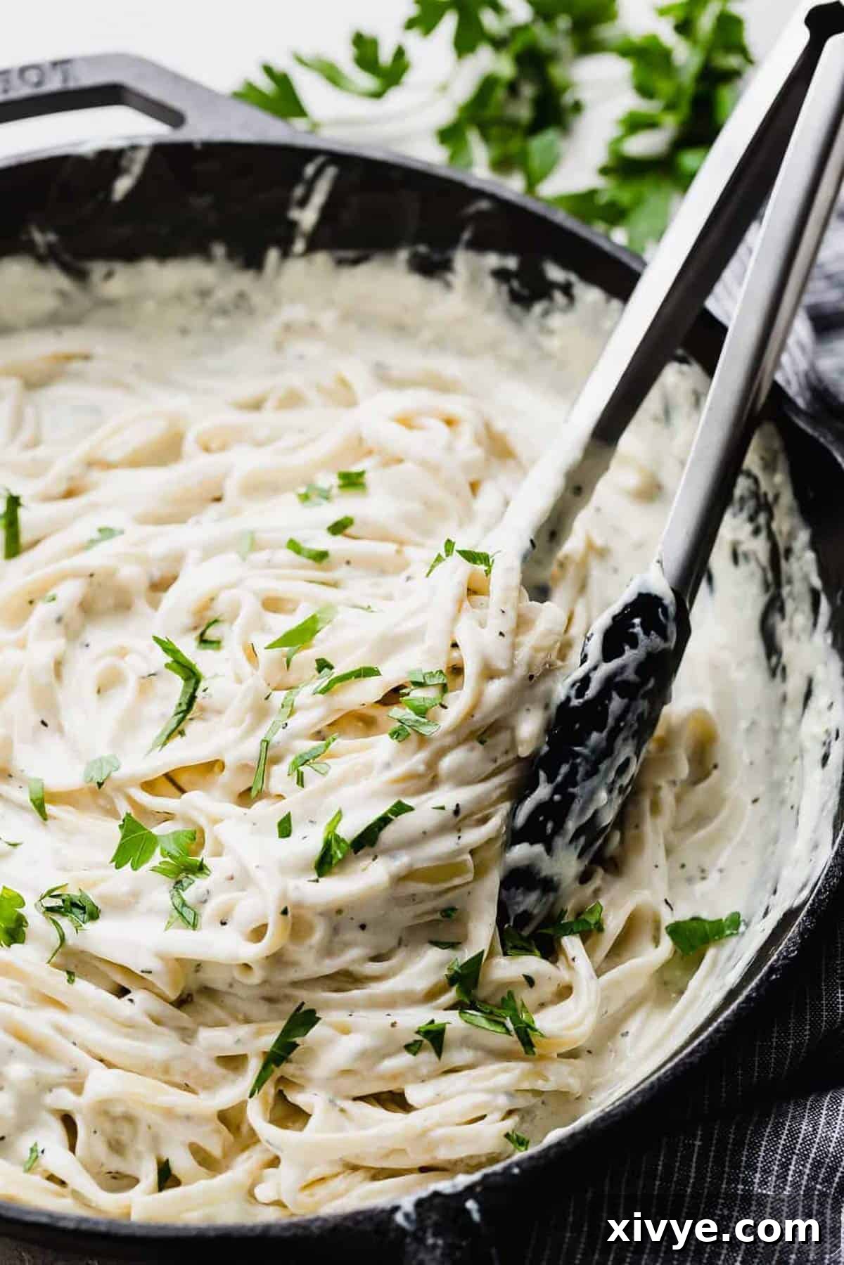 Fettuccine Alfredo in a black skillet topped with fresh parsley, ready to be served.