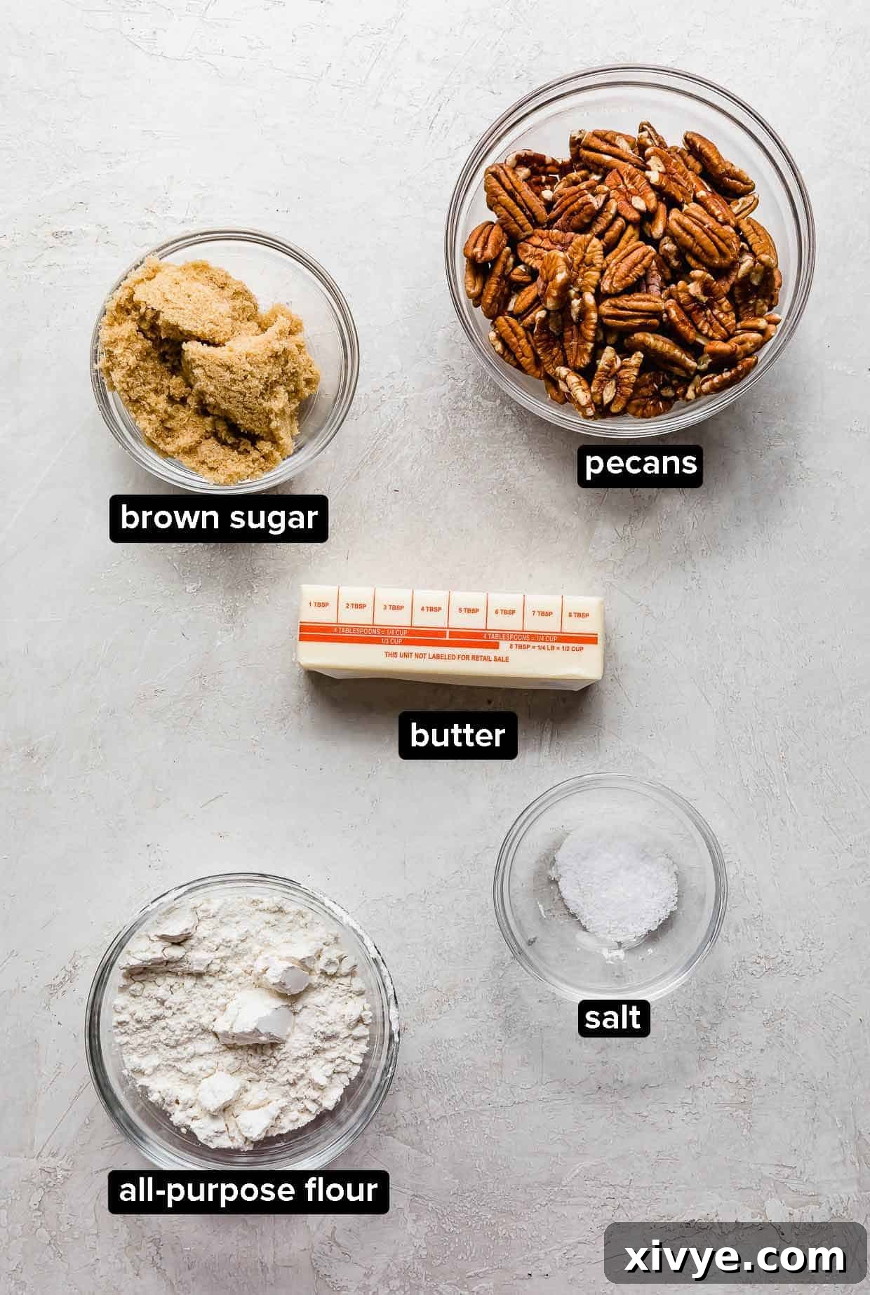 Effortless Sweet Potato Bake 4 Easy Sweet Potato Casserole pecan topping ingredients, including chopped pecans, brown sugar, all-purpose flour, and melted butter, portioned into glass bowls on a light gray background.