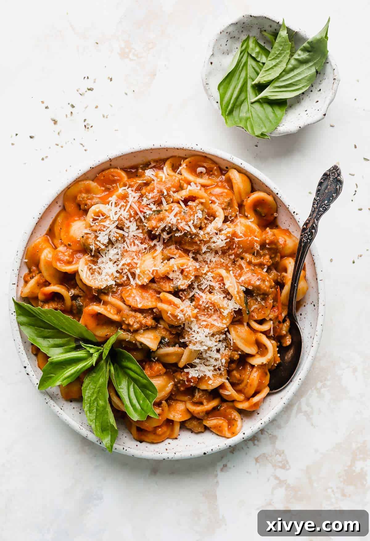 Classic Bolognese Ragù 5 Bolognese recipe in a white pasta plate topped with parmesan on a white background.