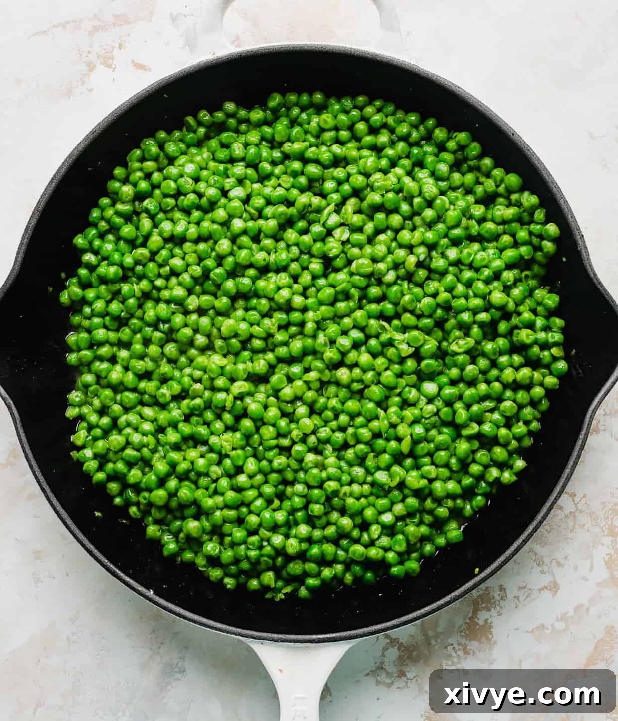 Elevate Your Frozen Peas 5 A skillet full of perfectly cooked green peas, glistening with butter and ready to be served, highlighting their vibrant color and tender texture.