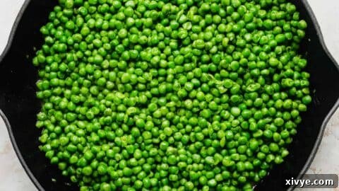 Elevate Your Frozen Peas 10 A skillet full of perfectly cooked green peas, glistening with butter and ready to be served.