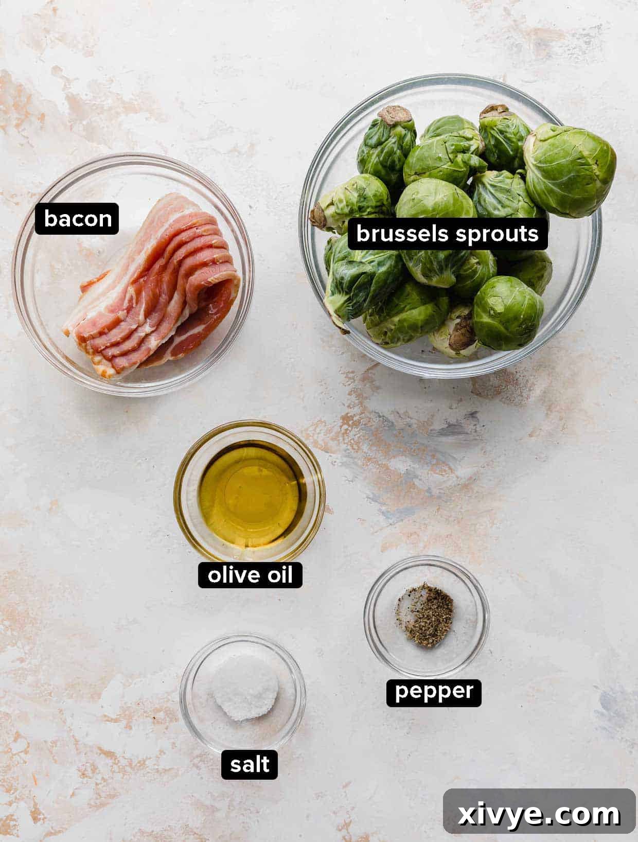 Roasted Brussels Sprouts with Bacon ingredients portioned into glass bowls on a white background; bacon, Brussels sprouts, olive oil, salt and pepper.