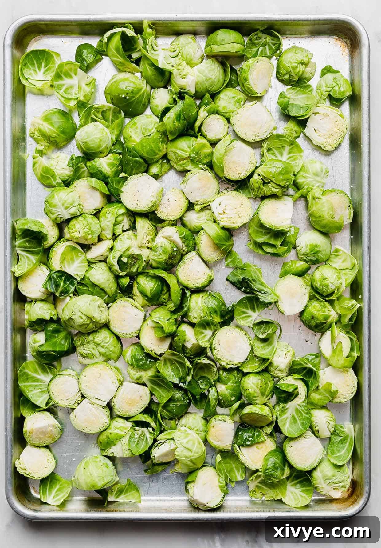 A sheet pan with chopped Brussels sprouts on it.