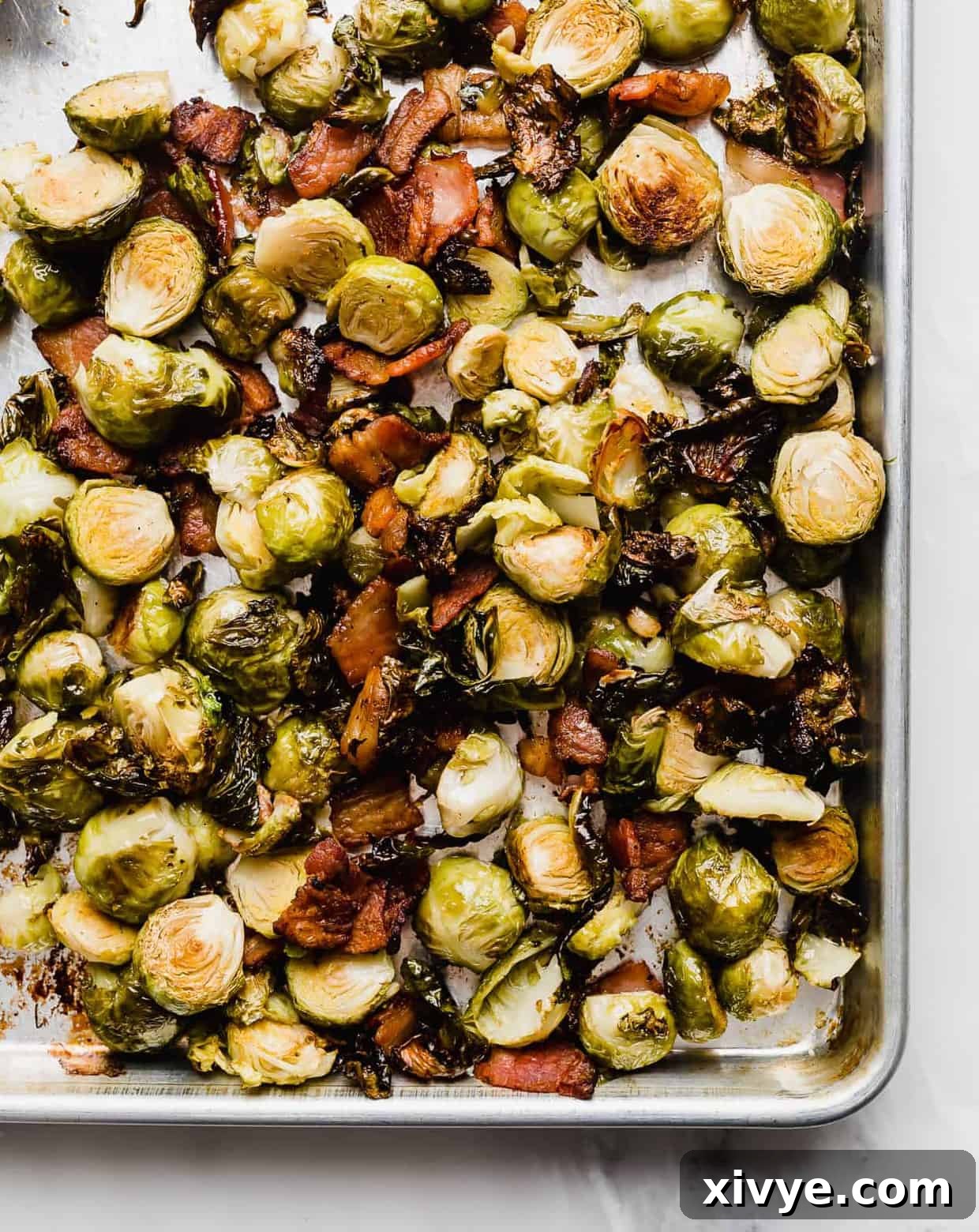 roasted Brussels sprouts and crispy bacon on a baking sheet.