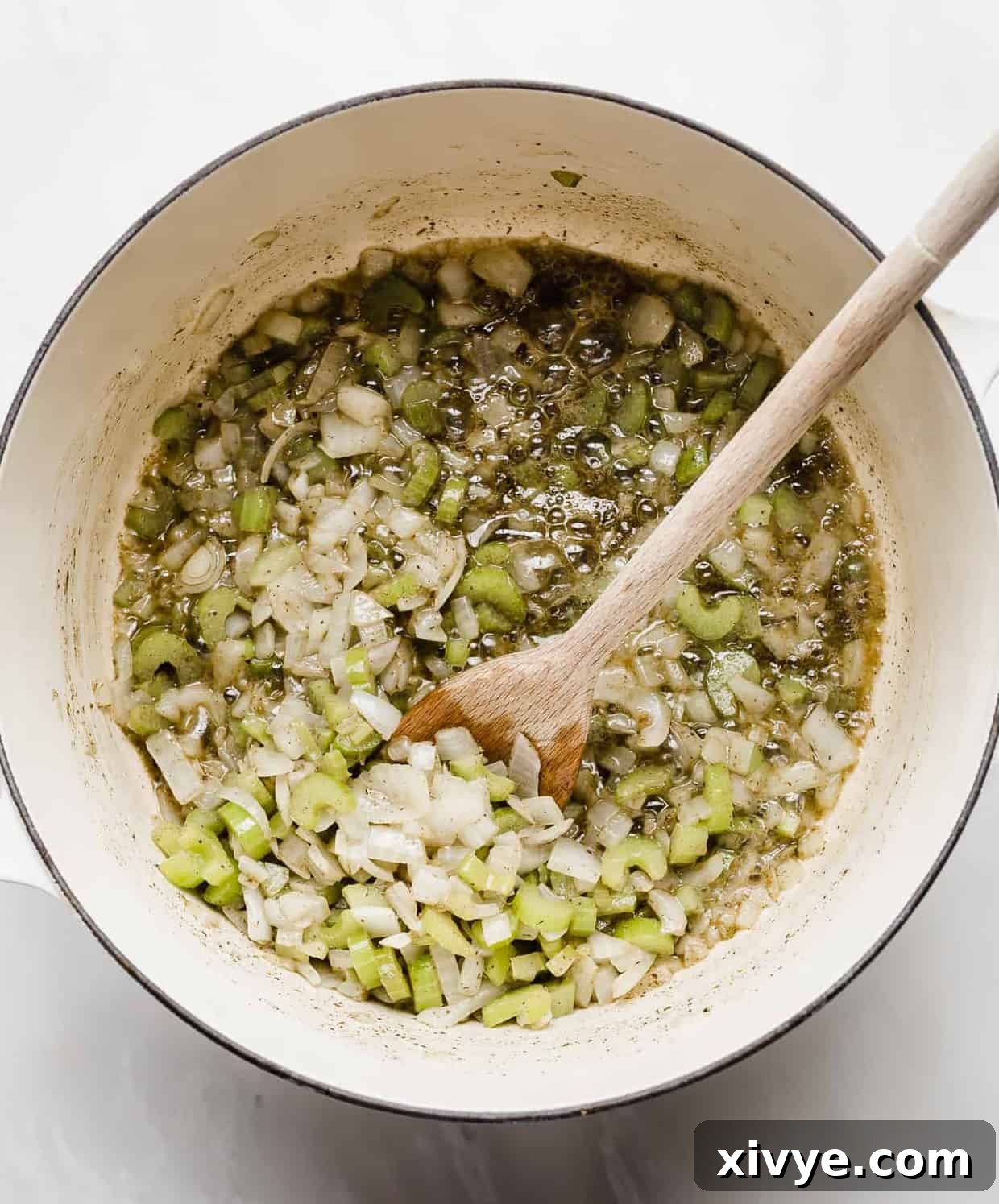 The Ultimate Thanksgiving Stuffing 4 A dutch oven with chopped onion and celery cooking in melted butter.