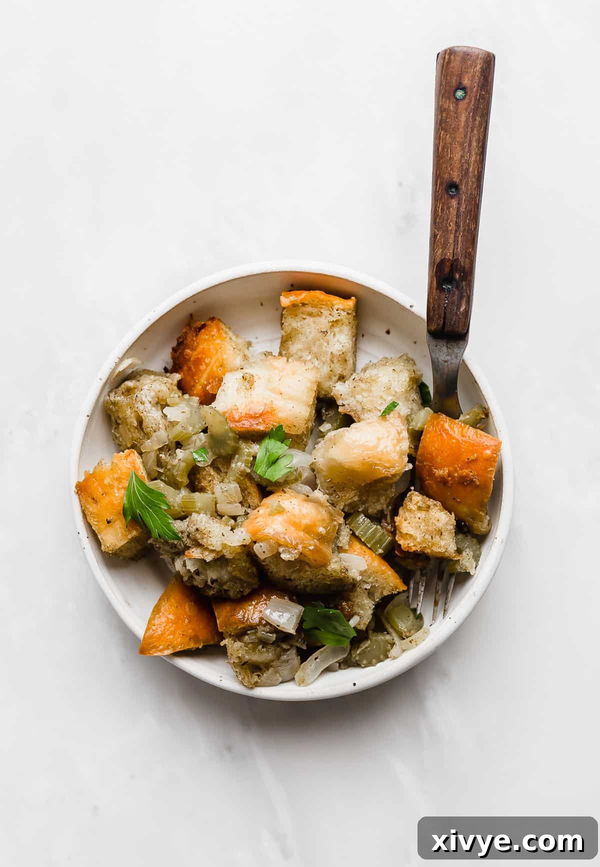 The Ultimate Thanksgiving Stuffing 9 A serving of Thanksgiving Stuffing on a white plate on a white background.